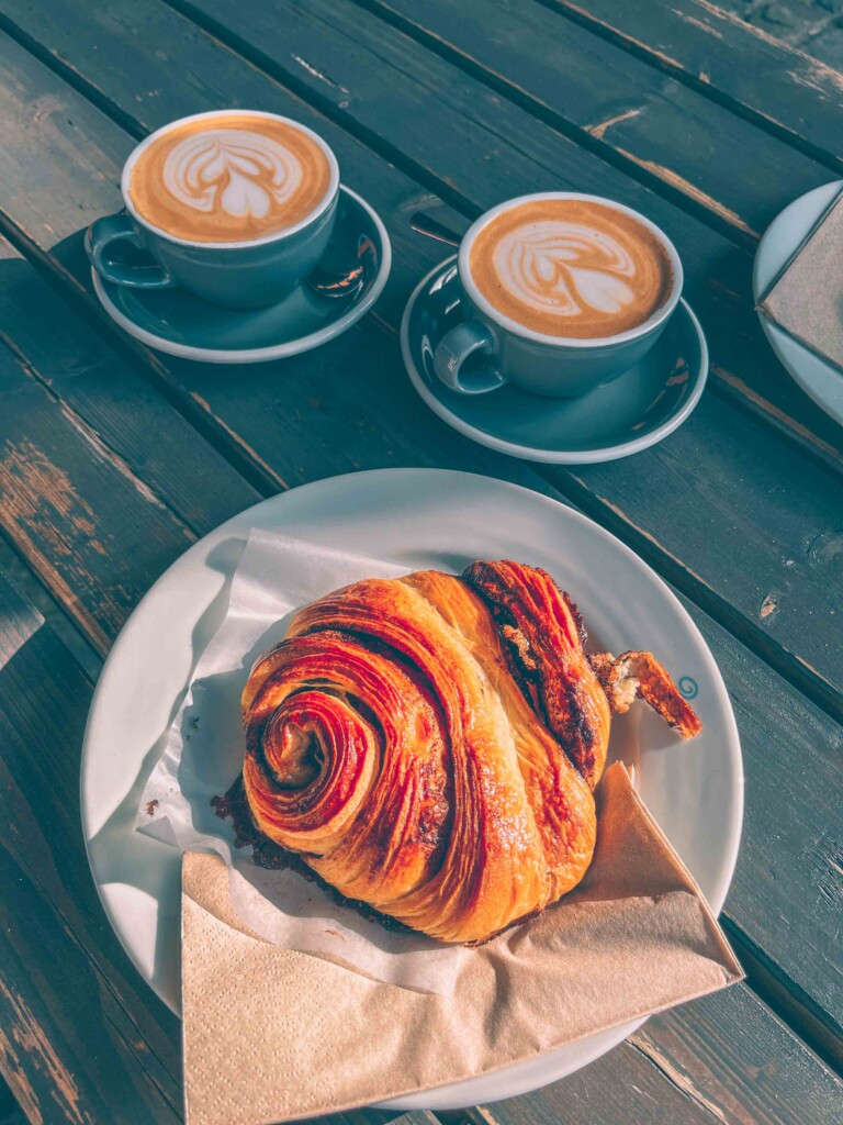 Two cups with amazing latte art designs and a golden Franzbr&ouml;tchen at Elbgold